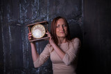 Pretty young woman holding a big clock. Faces series with different emotions.