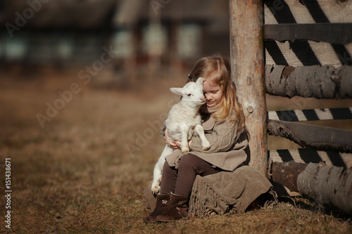 Carta da parati little girl with lamb on the farm