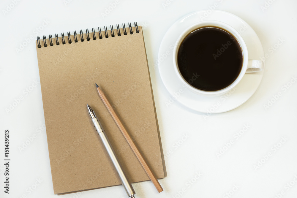 Workspace with notebook of craft paper, pencil, cup of coffee on white background. Image with copy space for your text. Workspace with notebook of craft paper, pencil, cup of coffee on white background. Image with copy space for your text.
