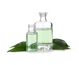 Perfume bottles and green leaves on white background