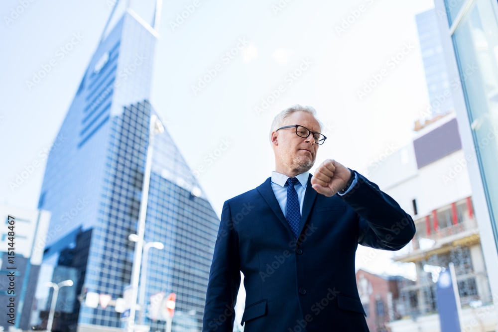 senior businessman checking time on his wristwatch senior businessman checking time on his wristwatch