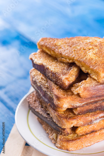 Flat lay pile of triangled french toast above blue wooden background table