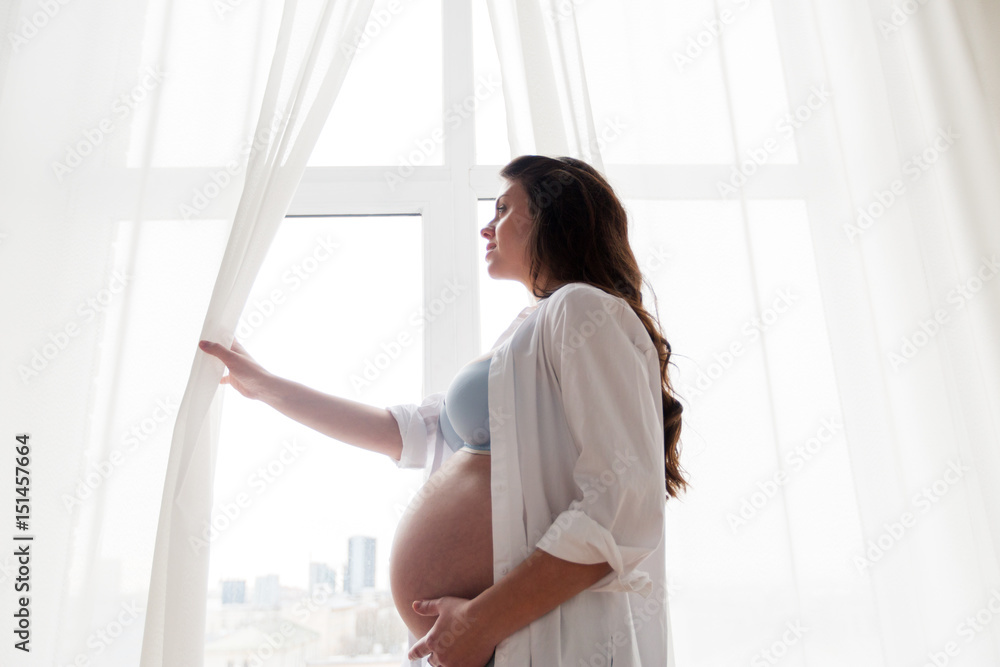 happy pregnant woman with big tummy at home