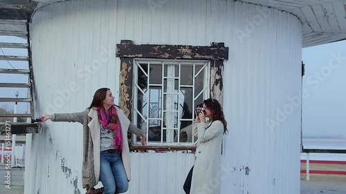 two young women are photographed on the background of the lighthouse.slow motion photo