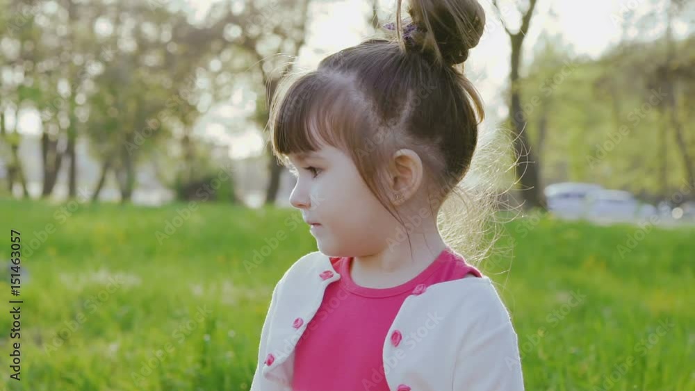 Cute little girl, looking to the camera in the sunny spring park Cute little girl, looking to the camera in the sunny spring park