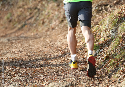 Muscular legs of the athlete runner from behind during the racin photo