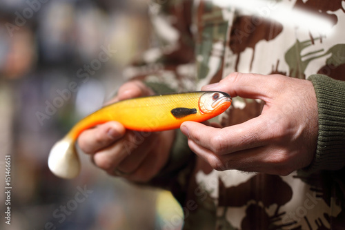 Jak łowić ryby? Wędkarz trzyma na dłoni przynętę. 