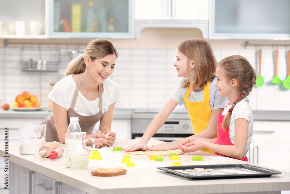 Young woman and her daughters cooking in kitchen