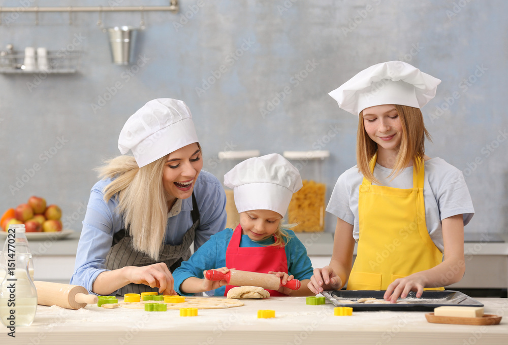 Young woman and her daughters cooking in kitchen Young woman and her daughters cooking in kitchen