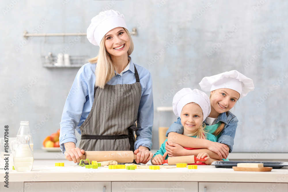 Young woman and her daughters cooking in kitchen Young woman and her daughters cooking in kitchen
