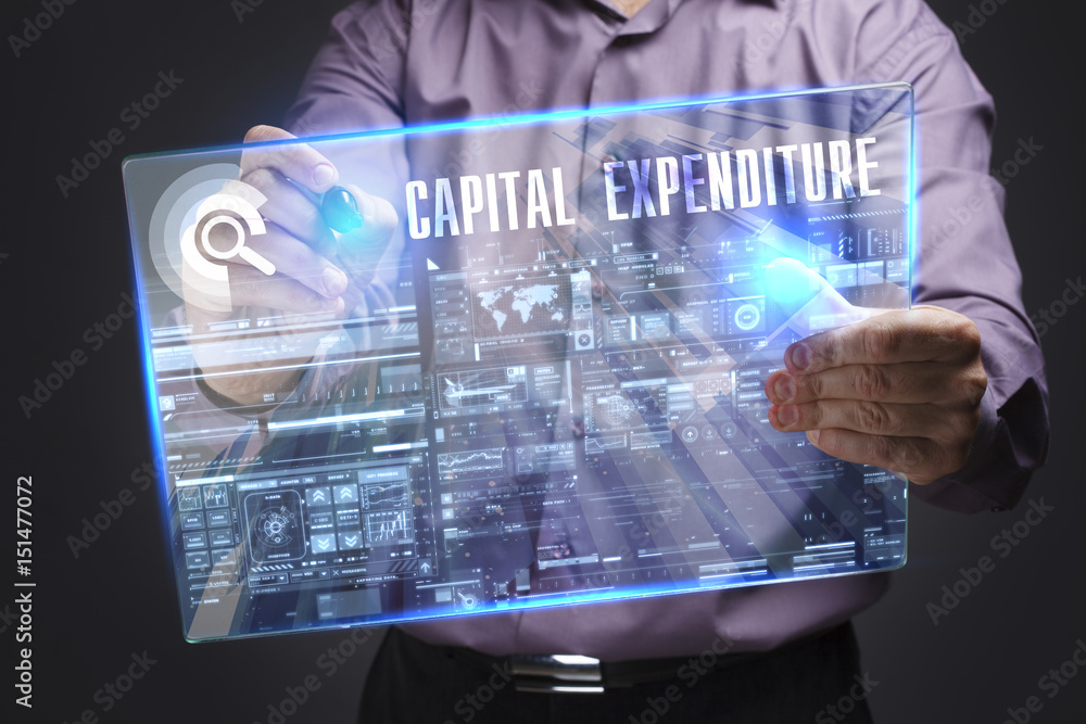 Business, Technology, Internet and network concept. Young businessman working on a virtual screen of the future and sees the inscription: Capital expenditure Business, Technology, Internet and network concept. Young businessman working on a virtual screen of the future and sees the inscription: Capital expenditure