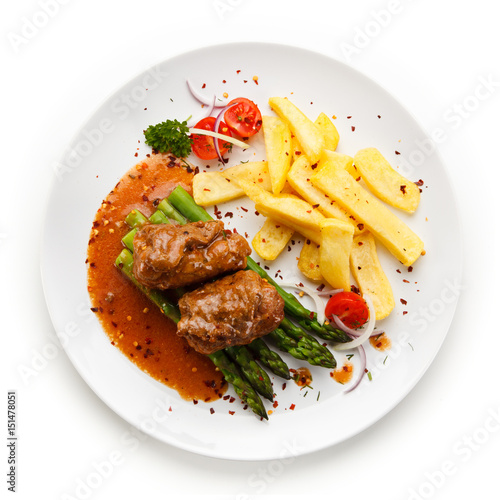 Wrapped pork chop with french fries and asparagus on white background