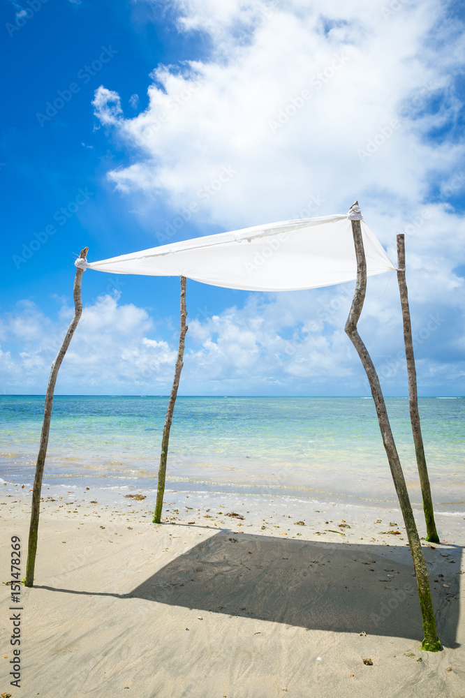 Rustic sun shade made from a sheet strung from sticks stands on an empty beach in Bahia, Brazil Rustic sun shade made from a sheet strung from sticks stands on an empty beach in Bahia, Brazil