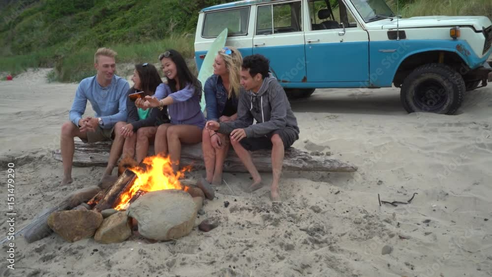Group of friends at beach hanging out by campfire Group of friends at beach hanging out by campfire