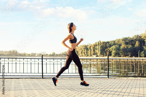Woman running by the lake at sunset. Sport and lifestyle concept