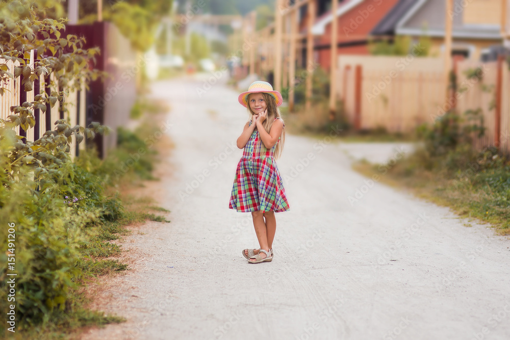 Sweet girl in retro dress and hat is walking along the village street in the summer Sweet girl in retro dress and hat is walking along the village street in the summer