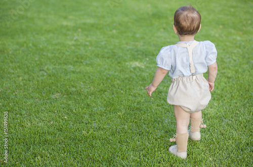 Little boy woth formal wear standing over green grass field