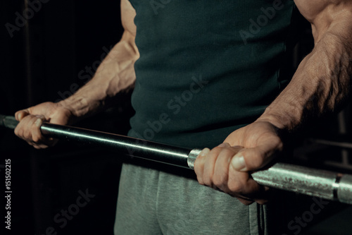 Inflated hands of a young guy close-up. Biceps on a black background