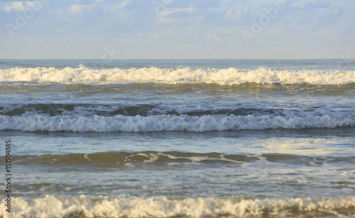 Wave running to the sand beach under blue sky