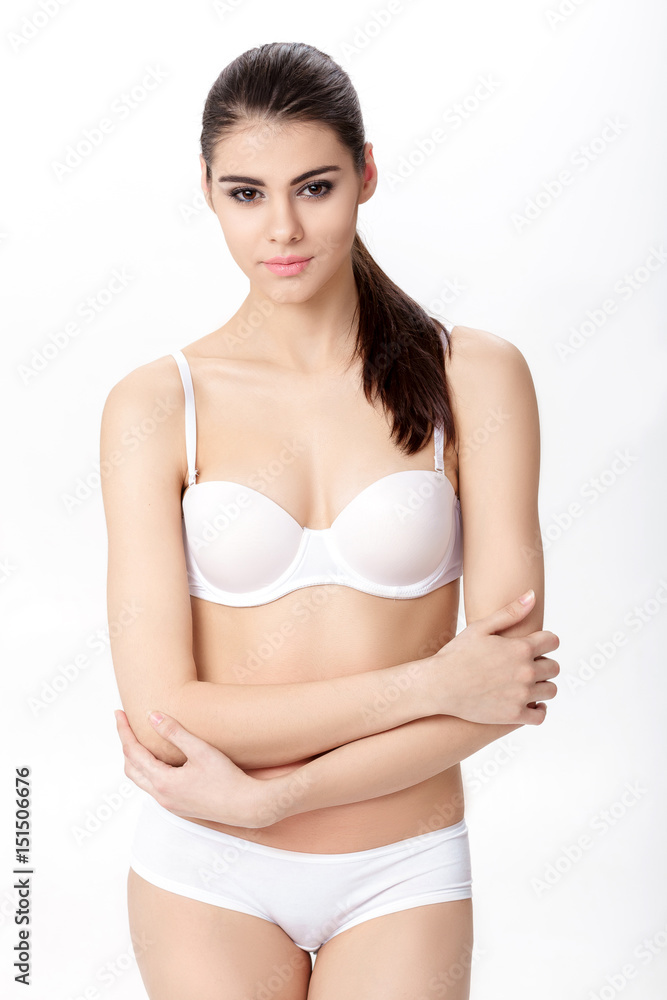 Obraz premium beautiful young brunette woman with perfect sporty body in white underwear on white background