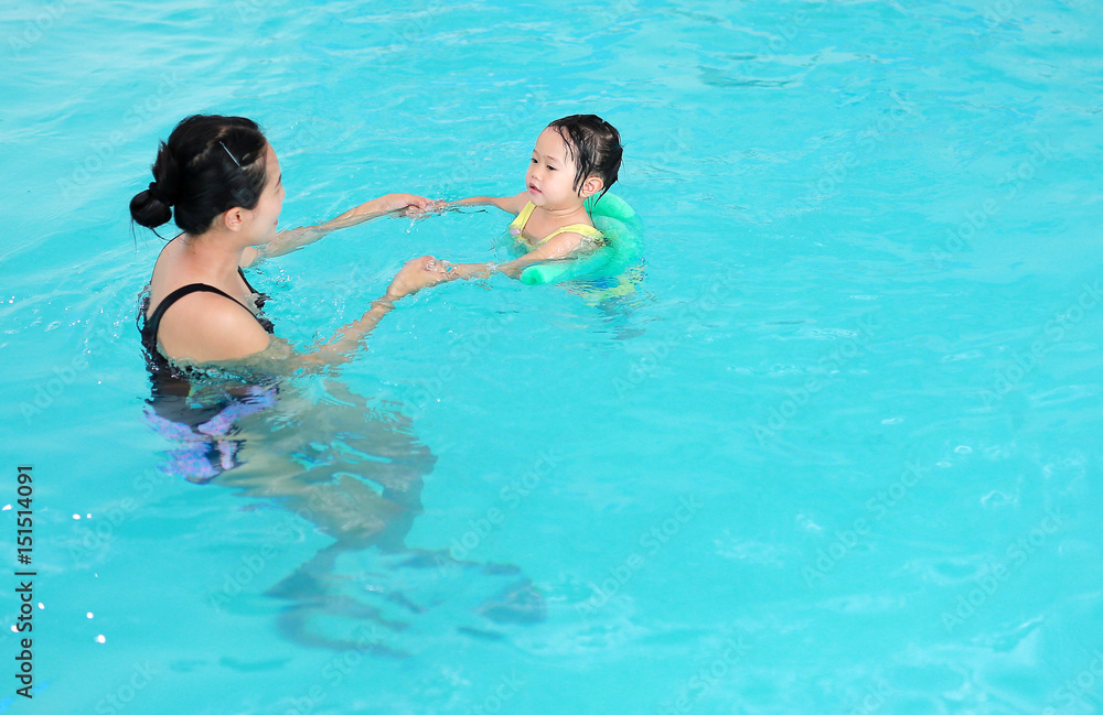 Close up mother teaching kid in swimming pool.