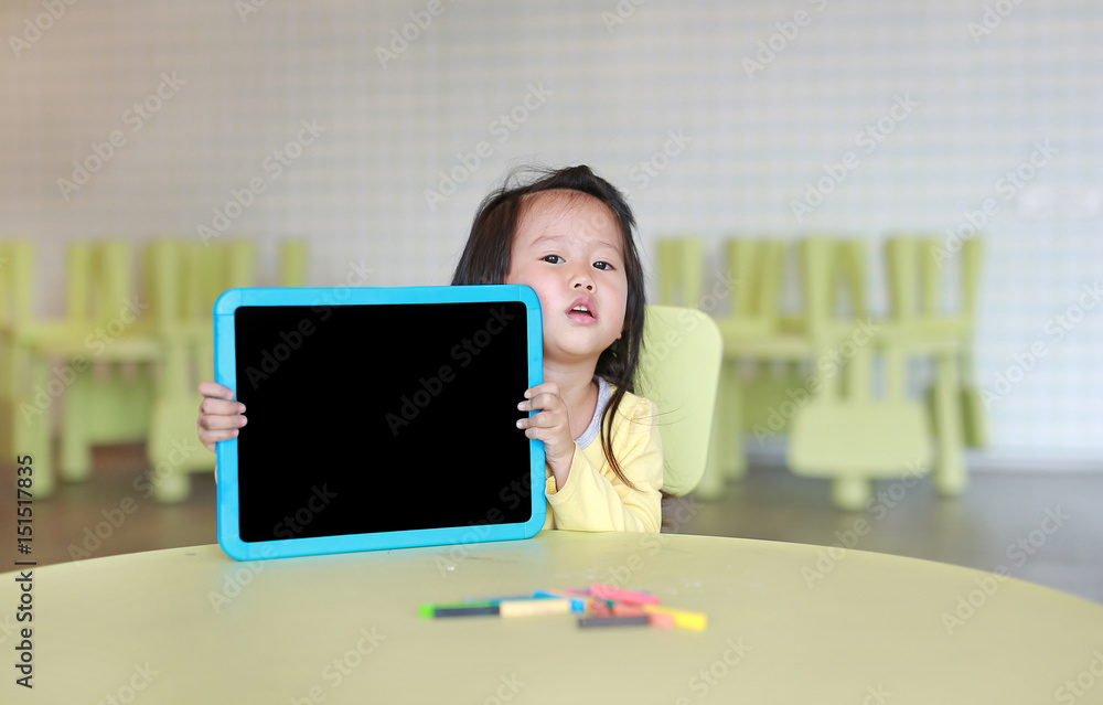 Cute asian child girl holding empty blackboard in playroom. Cute asian child girl holding empty blackboard in playroom.