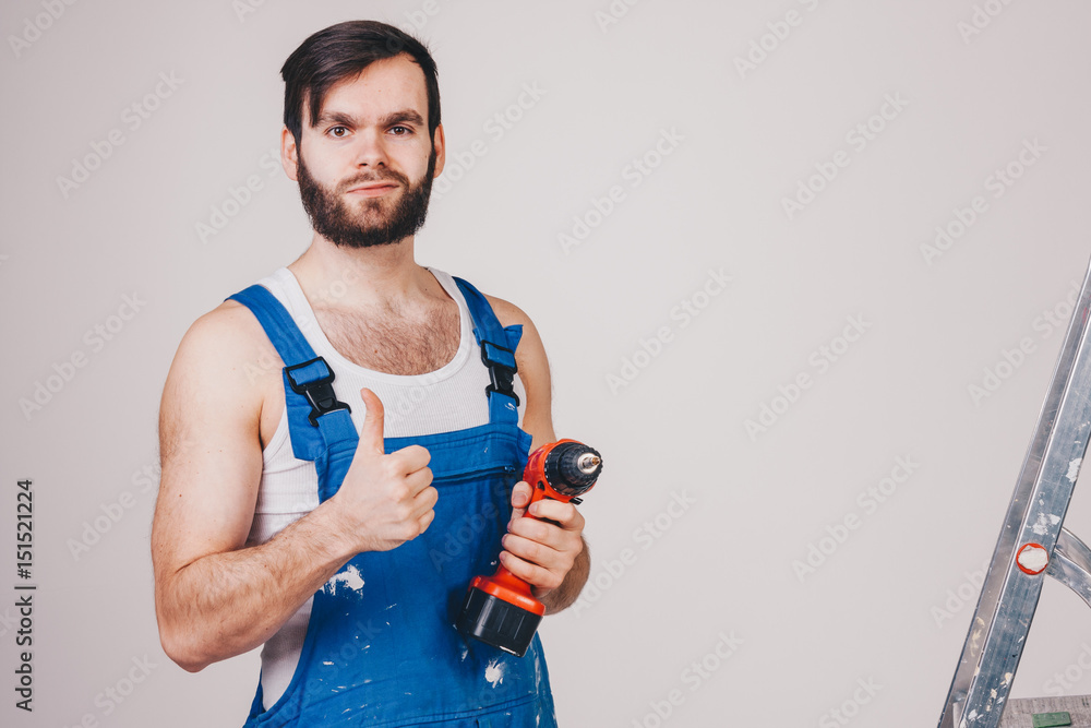 unshaved man in blue workman with a drill unshaved man in blue workman with a drill