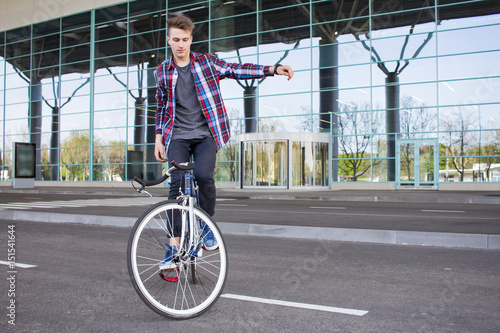 Young man balancing on his fixed gear bicycle on the empty mall parcking 