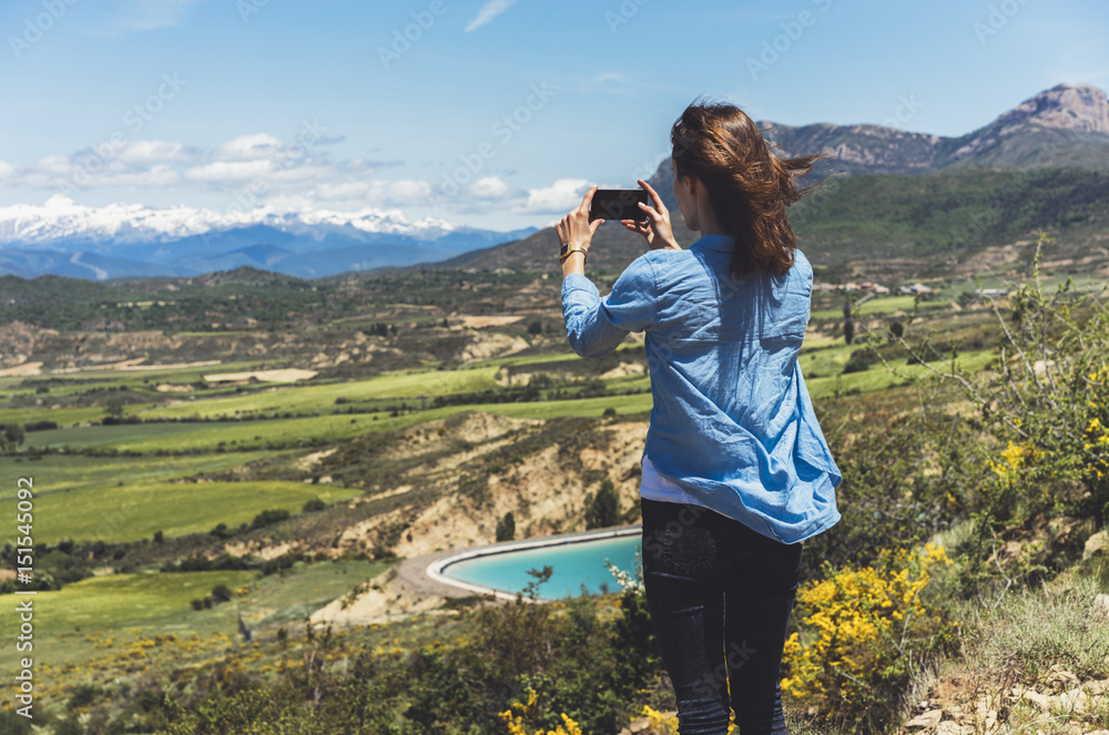 Hipster photograph on smart phone gadget mobile, mock up of blank screen. Girl traveler hold in hand mobile on background mountain landscape horizon. Tourist look map on adventure trip