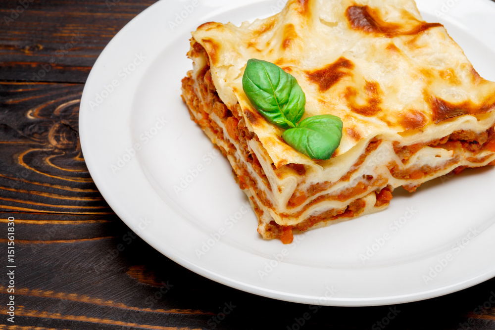 Portion of tasty lasagna on wooden backgound Portion of tasty lasagna on wooden backgound