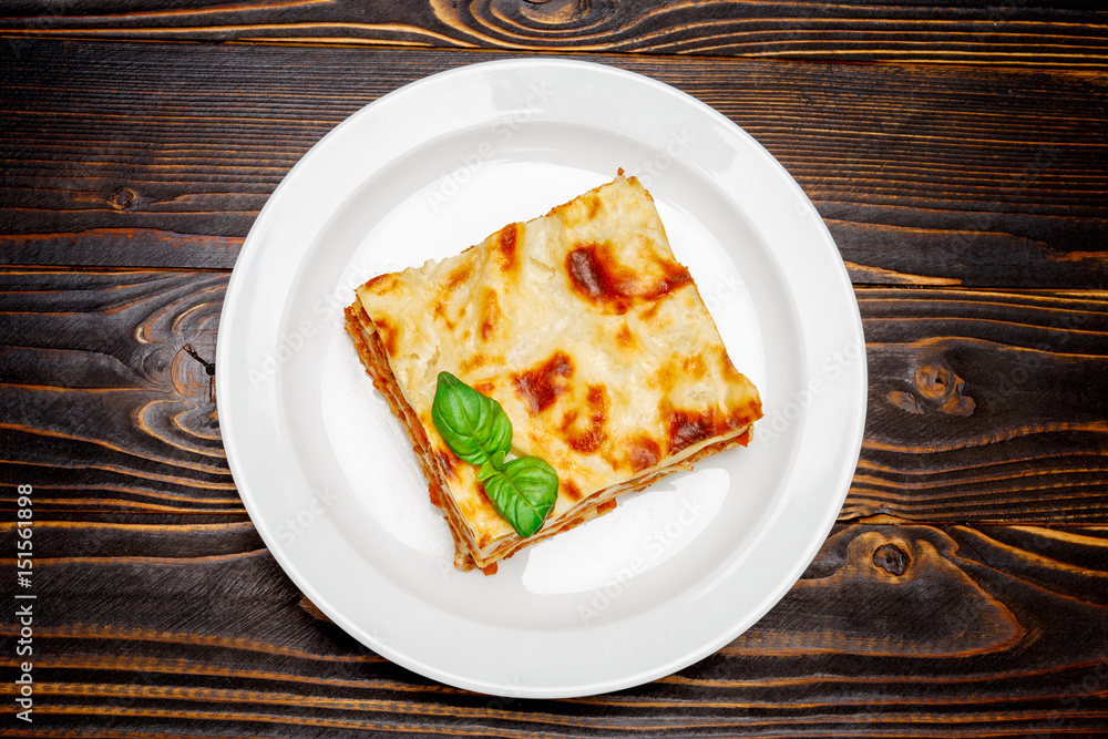 Portion of tasty lasagna on wooden backgound Portion of tasty lasagna on wooden backgound