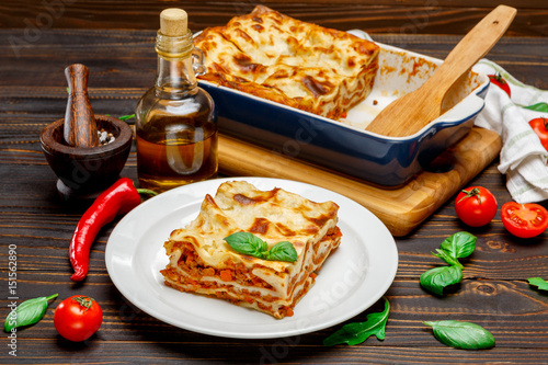 Portion of tasty lasagna on wooden backgound photo