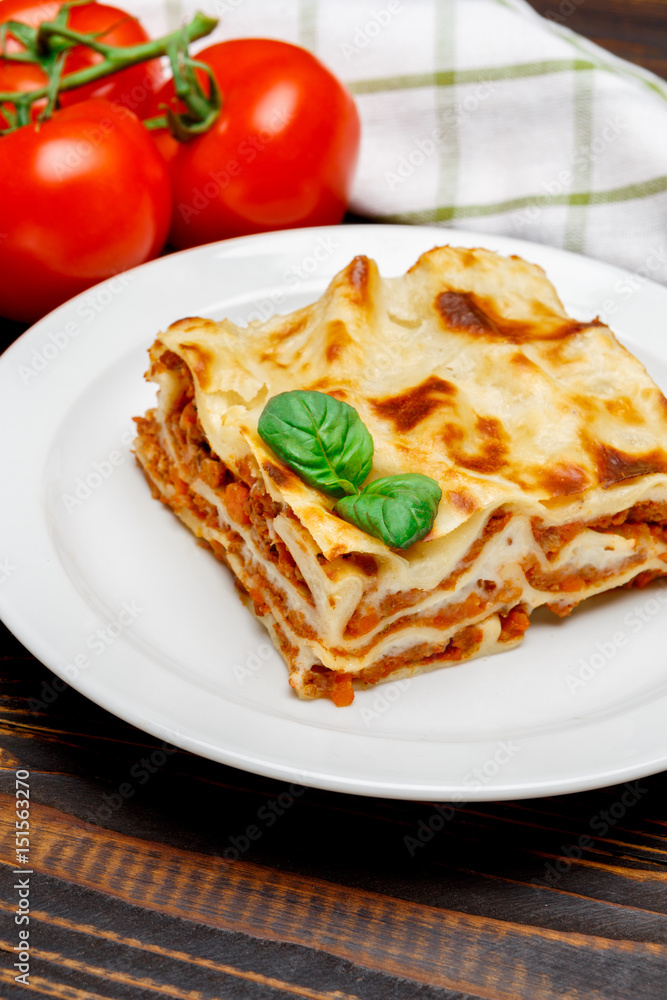Portion of tasty lasagna on wooden backgound