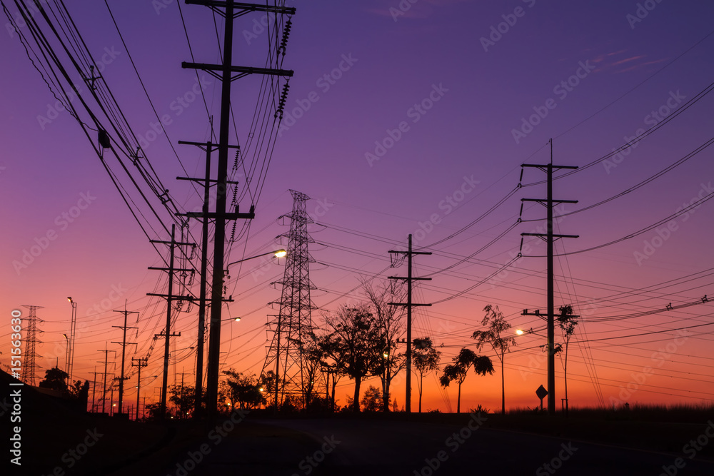 The silhouette of the high voltage towers, electricity post and tree which have a beautiful background.
