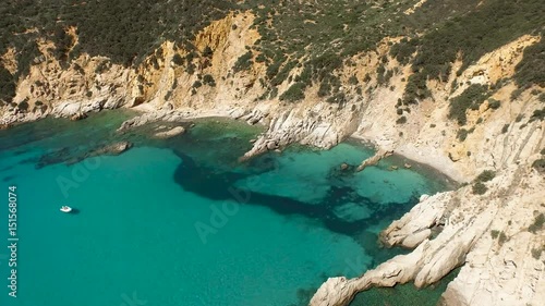 Drone fly over sardinia coastline and colorful turquoise mediterranean sea surraunded by high cliff and ancient ruins of a watchtower