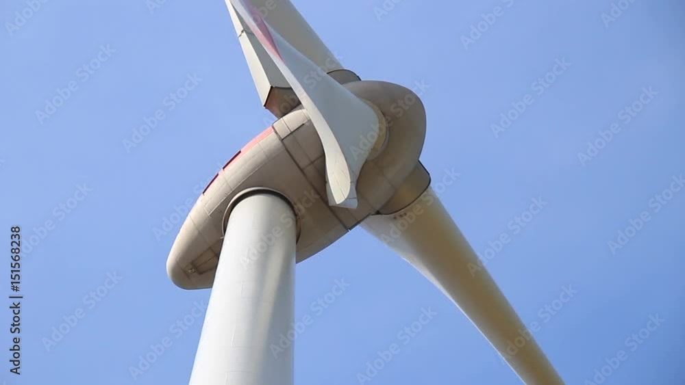 Close up of rotating wind turbine propeller blades in the blue sky - view from the ground Close up of rotating wind turbine propeller blades in the blue sky - view from the ground