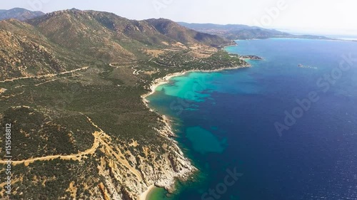 Drone fly over sardinia coastline and colorful turquoise mediterranean sea surraunded by high cliff and ancient ruins of a watchtower