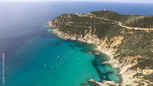 Drone fly over sardinia coastline and colorful turquoise mediterranean sea surraunded by high cliff and ancient ruins of a watchtower photo