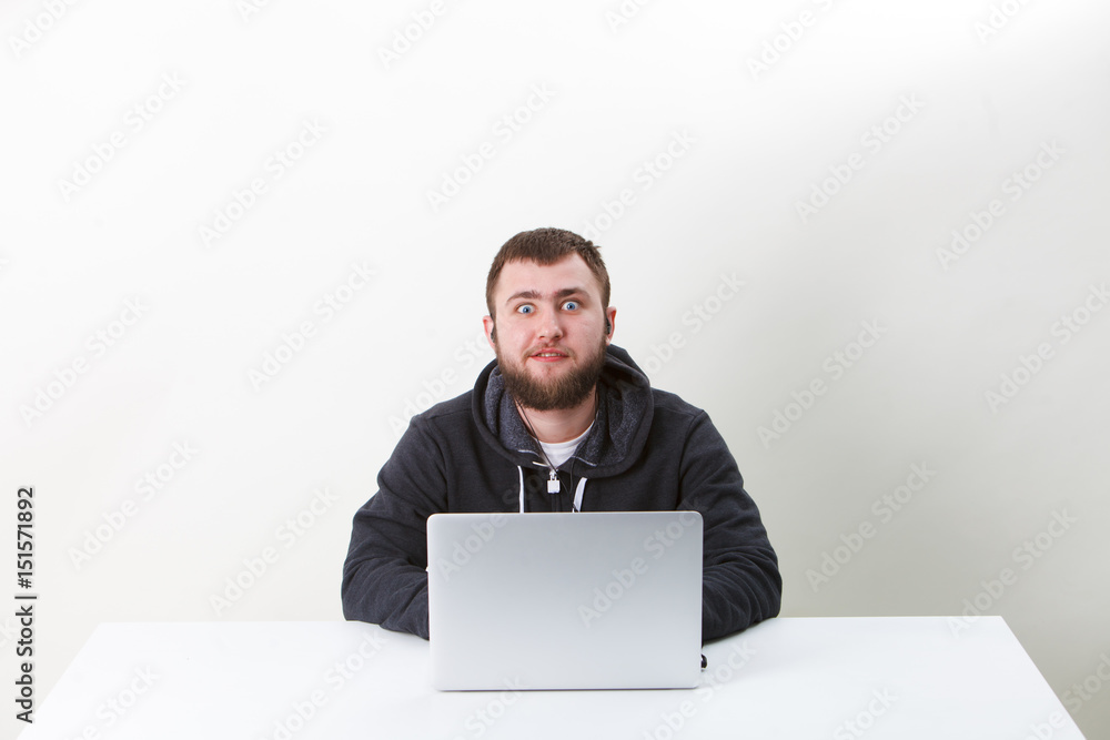 The programmer works behind the laptop. Isolated, one person on a white background. He is calm. The programmer works behind the laptop. Isolated, one person on a white background. He is calm.