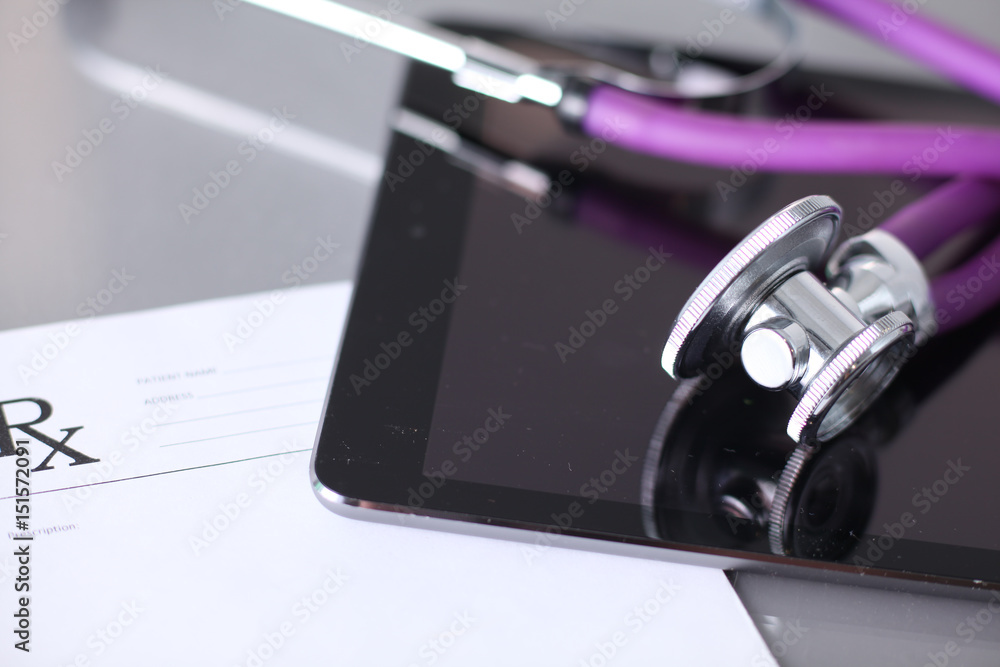 Tablet computer with a stethoscope lie on a table Tablet computer with a stethoscope lie on a table