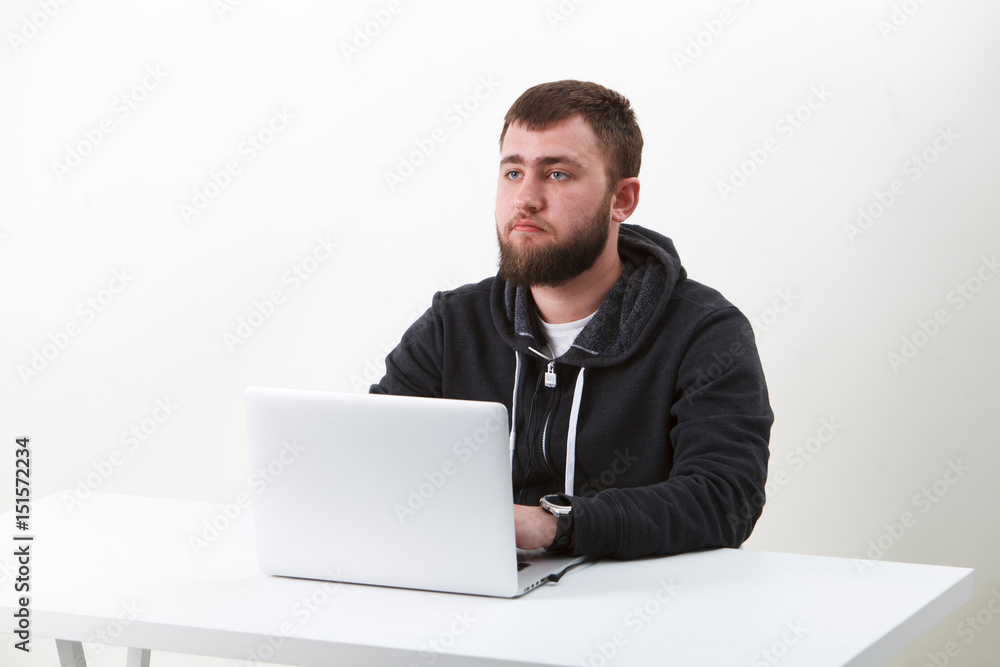 The programmer with glasses works behind the laptop. Isolated, one person on a white background. He is calm. The programmer with glasses works behind the laptop. Isolated, one person on a white background. He is calm.
