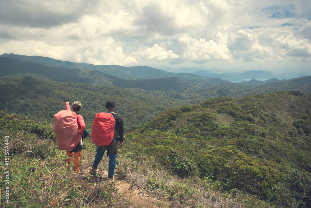 Two young backpackers enjoying a beautiful view of mountain range. Travel lifestyle