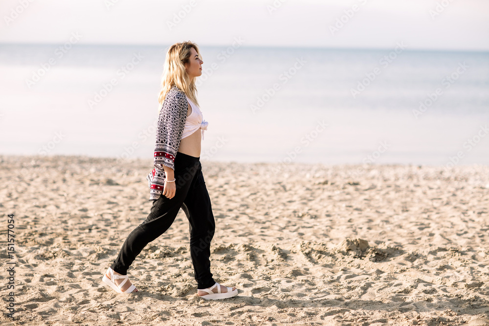 Blonde girl on the beach of the sandy beach by the sea