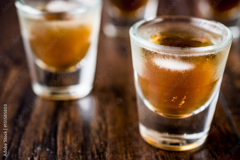 Whiskey Shots with ice on dark wooden surface. Whiskey Shots with ice on dark wooden surface.
