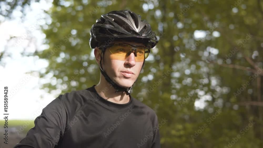Portrait of young sports man wears yellow glasses, riding bicycle on the tree forest road, sunny spring day Portrait of young sports man wears yellow glasses, riding bicycle on the tree forest road, sunny spring day