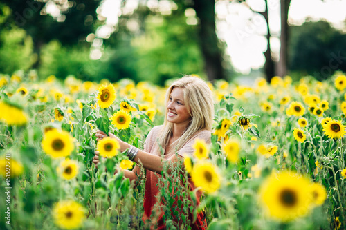 portrait of beautiful young blonde woman grabbing sunflower and smiling again