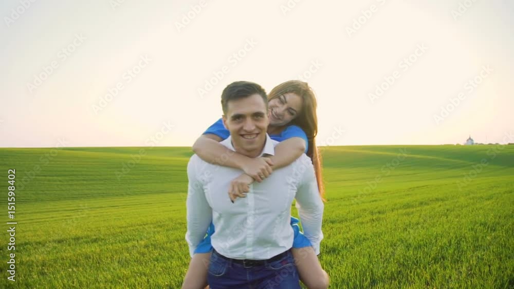 Happy couple on the wheat field. Man carrying his girl on shoulders on sunset Happy couple on the wheat field. Man carrying his girl on shoulders on sunset