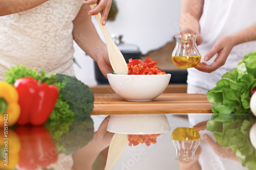Closeup of two women are cooking in a kitchen. Friends having fun while preparing fresh salad