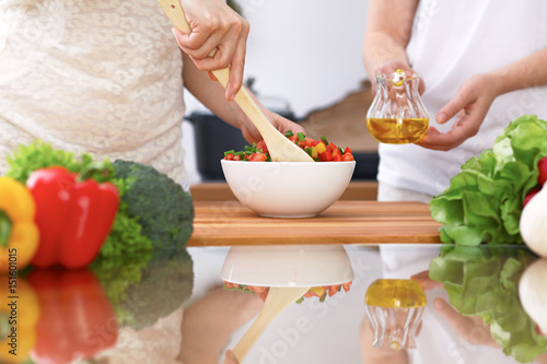 Closeup of two women are cooking in a kitchen. Friends having fun while preparing fresh salad