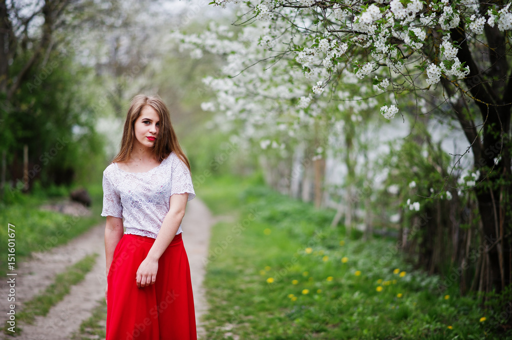 Portrait of beautiful girl with red lips at spring blossom garden, wear on red dress and white blouse. Portrait of beautiful girl with red lips at spring blossom garden, wear on red dress and white blouse.